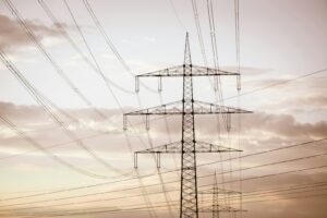 Hoogspanningsleidingen op hoge metalen torens strekken zich uit over de horizon tegen een bewolkte hemel en illustreren de energie-infrastructuur.