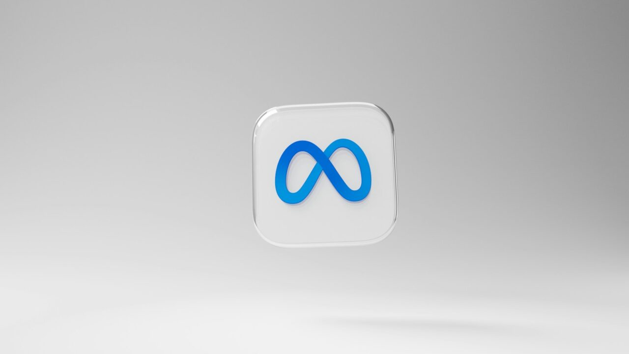 Een 3D-icoon met een blauw META-logo (voorheen Facebook) wordt weergegeven op een transparant vierkant met afgeronde randen. De achtergrond is een lichtgrijze gradiënt. Het ontwerp is eenvoudig en modern, met de nadruk op de aparte vorm en kleur van het oneindigheidssymbool tegen de neutrale achtergrond.