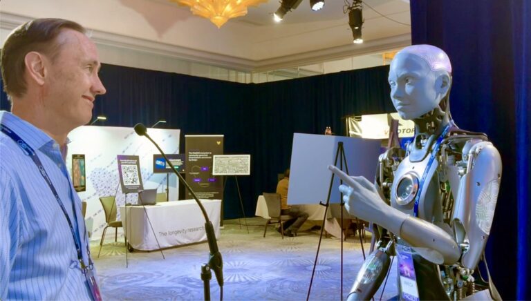Een man staat tegenover een humanoïde robot in een conferentiesetting. De robot wijst met één hand naar voren. Op de achtergrond zijn informatiestands en displays te zien, onder felle lampen.