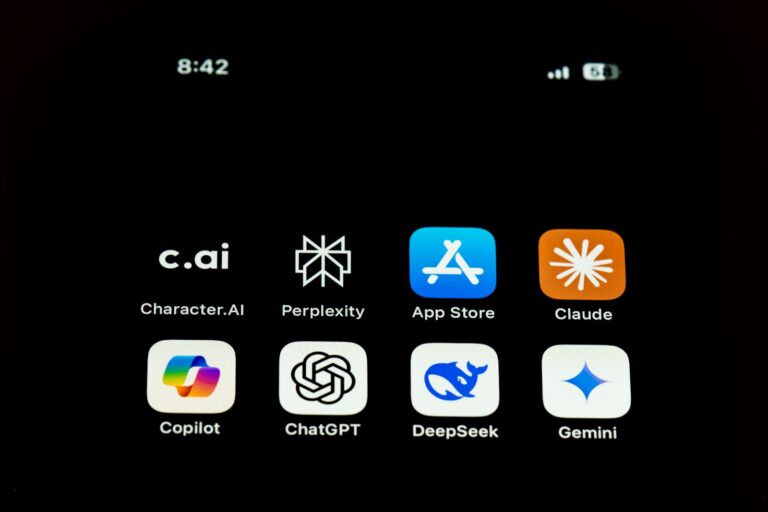 Op een smartphonescherm worden acht app-iconen weergegeven: Character.AI, Perplexity, App Store, Claude, Copilot, ChatGPT, DeepSeek en Gemini. De tijd linksboven is 8:42 en de batterij- en signaaliconen rechtsboven.